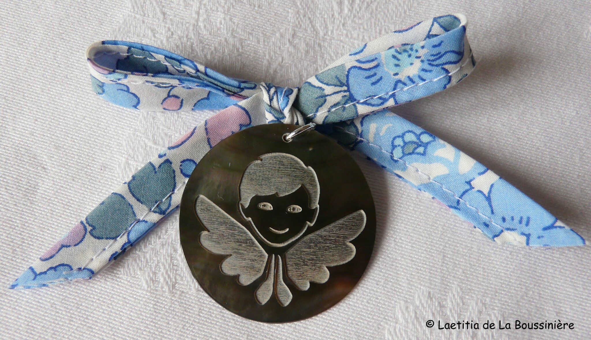 Médaillon d'ange en nacre (sur ruban Betsy bleu clair et rose)