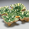 A rare resist-decorated green, cream and amber-glazed pottery quatrefoil footed dish, Tang dynasty (618-907)